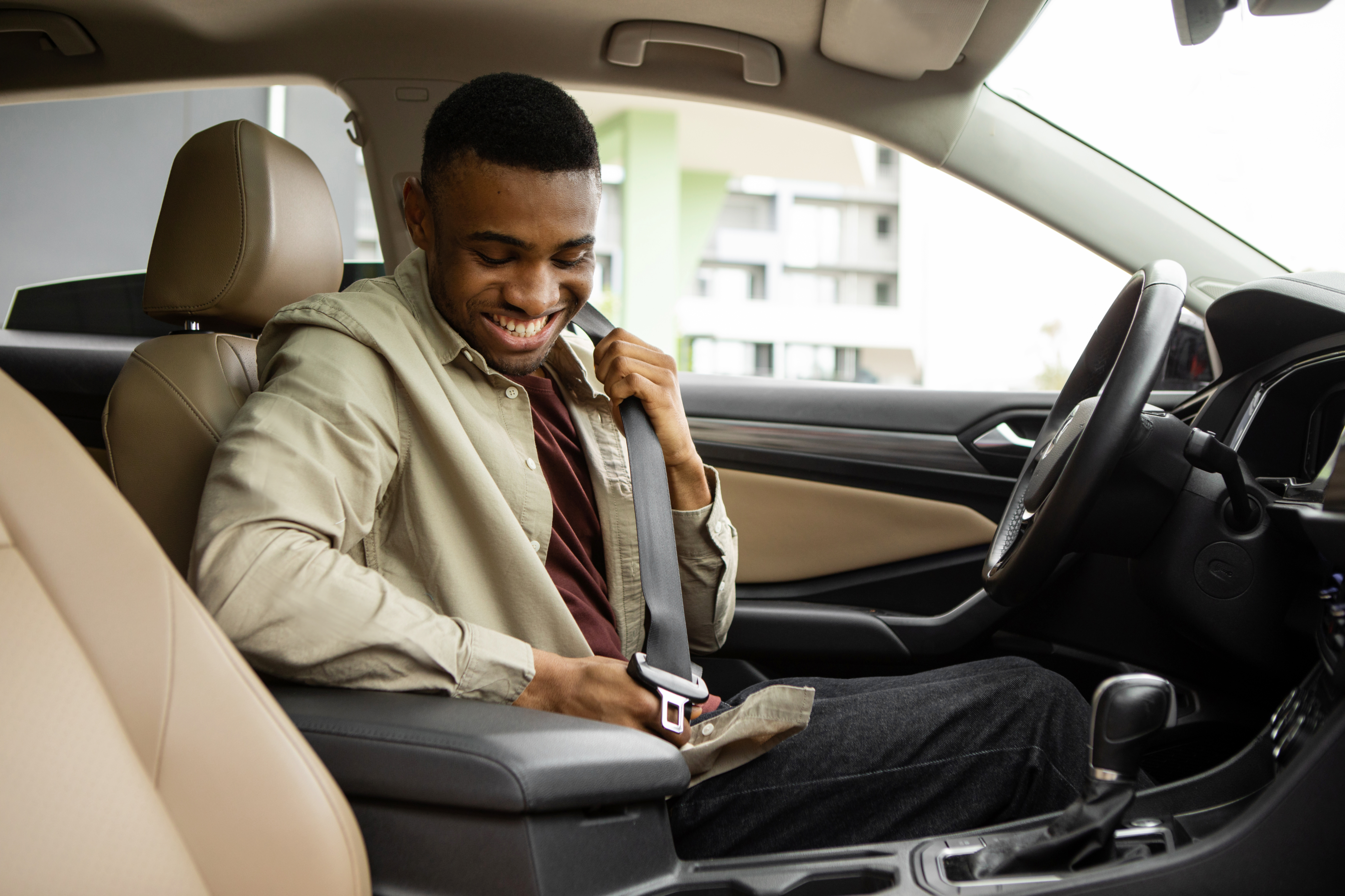 After finding out how to get a car loan with a great interest rate from a credit union, a man buckles himself into his new car.