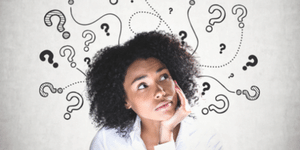 Young African American woman with chin resting in hand.  With a background full of question marks, she is pondering questions in reference to choosing the right credit card